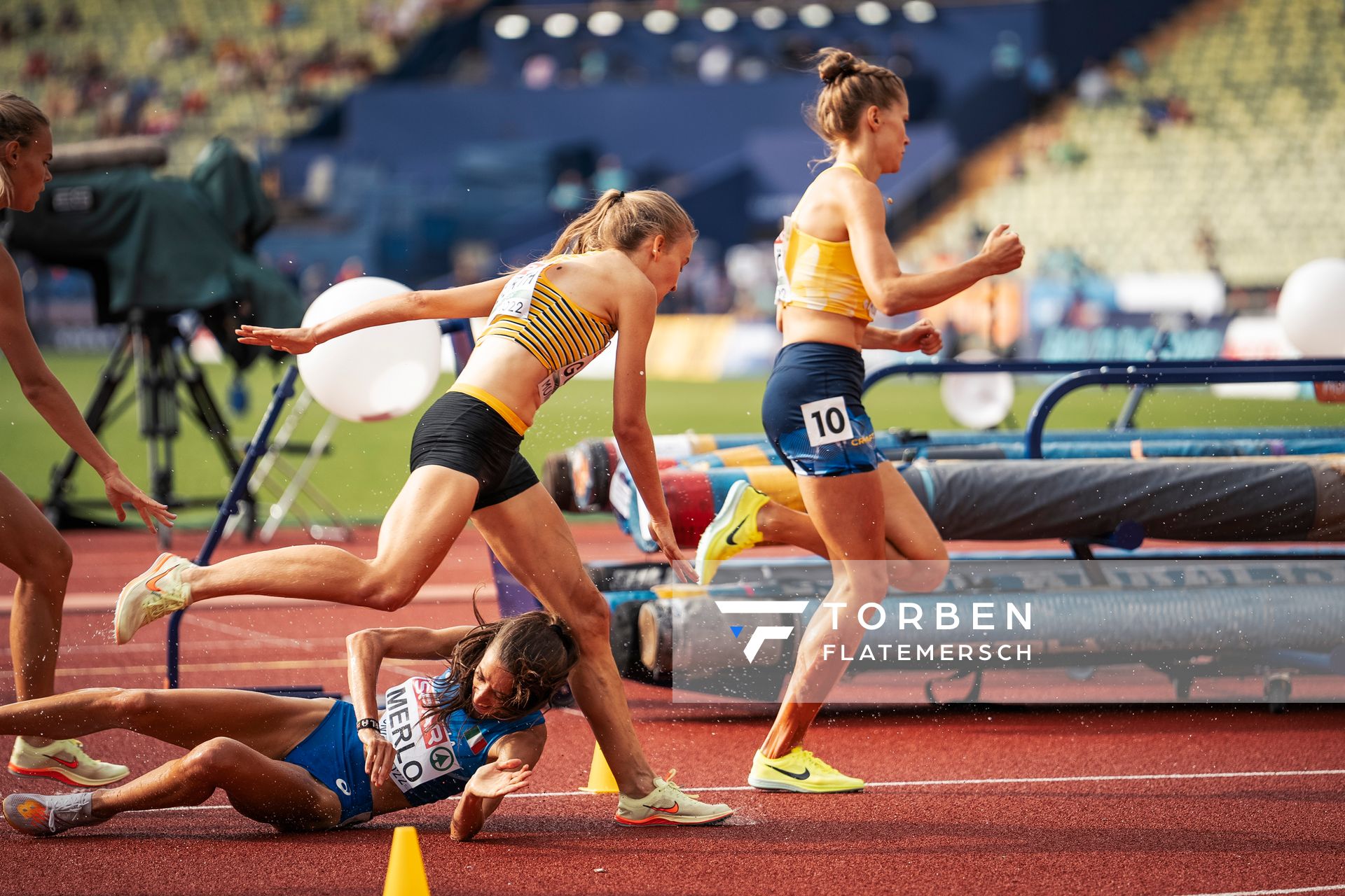 Olivia Guerth (GER) muss ueber Martina Merlo (ITA) springen, die gestuerzt ist im 3000m Hindernis Vorlauf am 18.08.2022 bei den Leichtathletik-Europameisterschaften in Muenchen