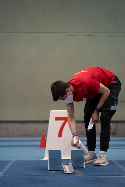 Ein Kampfrichter desinfiziert den Startblock; Niedersaechsische Hallenmeisterschaften am 22.01.2022 in der Leichtathletikhalle im Sportleistungszentrum Hannover